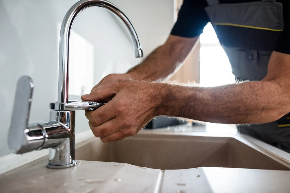 Intérieur cuisine moderne avec robinet chromé en gros plan d'où s'échappe une goutte d'eau