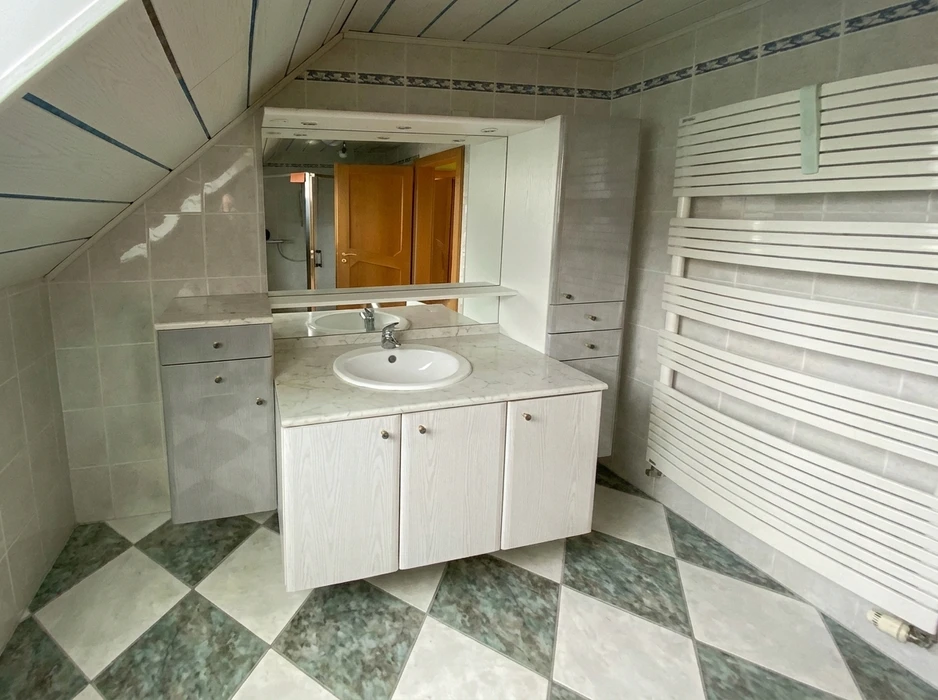 Salle de bain sous combles avec vasque encastrée sur plan de travail marbre blanc, meuble sous-vasque bois laqué blanc 3 portes, miroir armoire de toilette lumineux