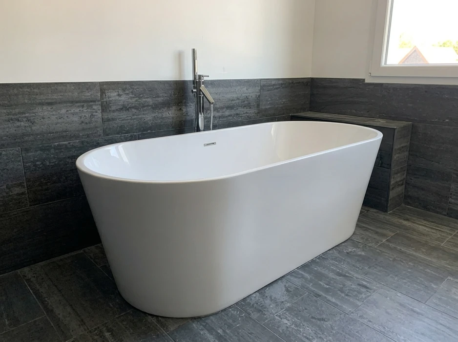 Salle de bain sous combles avec vasque encastrée sur plan de travail en marbre blanc veiné, meuble-lavabo blanc avec portes battantes ouvertes