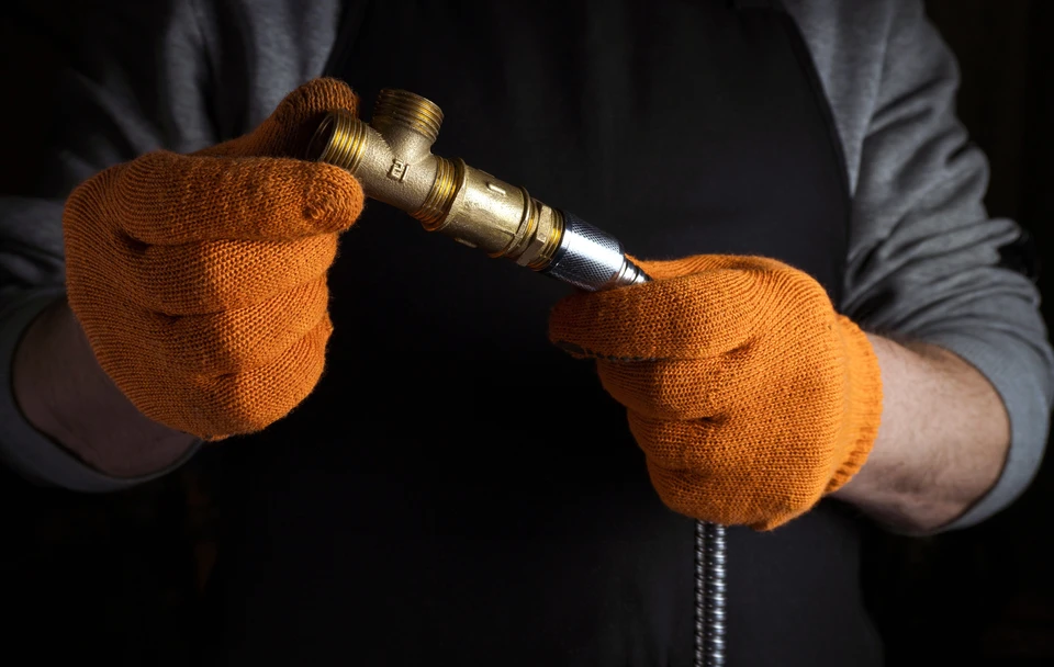 Plombier effectuant la réparation d'un robinet de salle de bain, utilisant une clé à molette pour dévisser les raccords